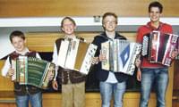 Vier Jungen stehen nebeneinander und halten Akkordeons. Sie lachen und tragen Freizeitkleidung. Die Szene wirkt fröhlich und musikalisch inspiriert.