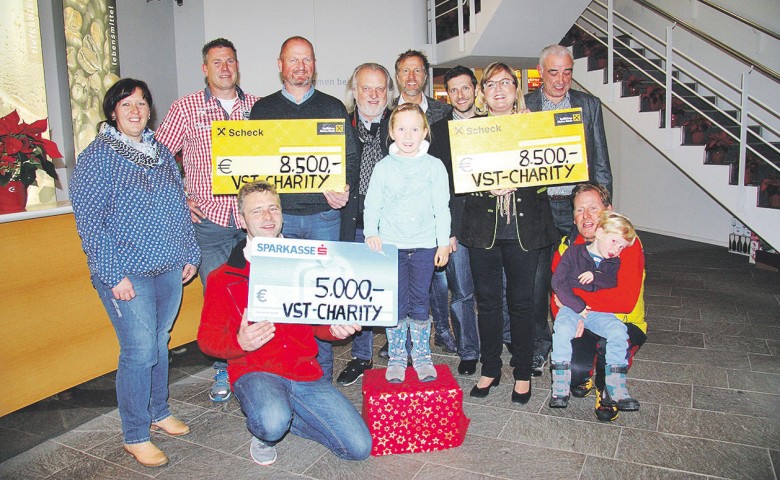 Gruppe von Menschen, die zwei große Spendenschecks für wohltätige Zwecke hält; zwei Schecks mit den Beträgen 5.000 und 8.500 Euro, alle lächeln.