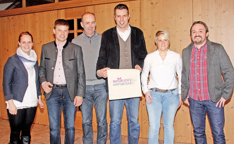 Sechs Personen stehen lächelnd in einer Reihe in einem Raum mit Holzwänden. Eine Person hält eine Tasche, auf der "Atemschutz Reparaturservice" steht.