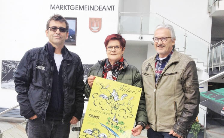 Drei Personen stehen vor einem Gebäude mit der Aufschrift "Marktgemeindeamt". Eine Person hält ein gelbes Plakat in der Hand.