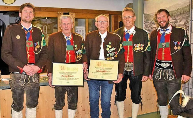 Fünf Männer in traditioneller Tiroler Tracht stehen nebeneinander. Zwei von ihnen halten Zertifikate in der Hand. Alle tragen festliche Kleidung.