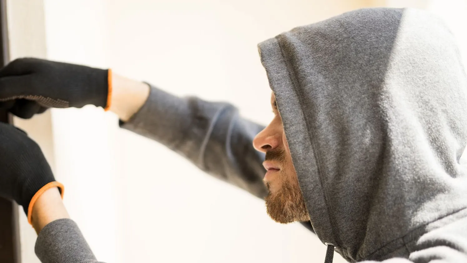 Einbrecher_profile-view-man-with-hoodie-trying-pick-lock-house-forcing-his-entry