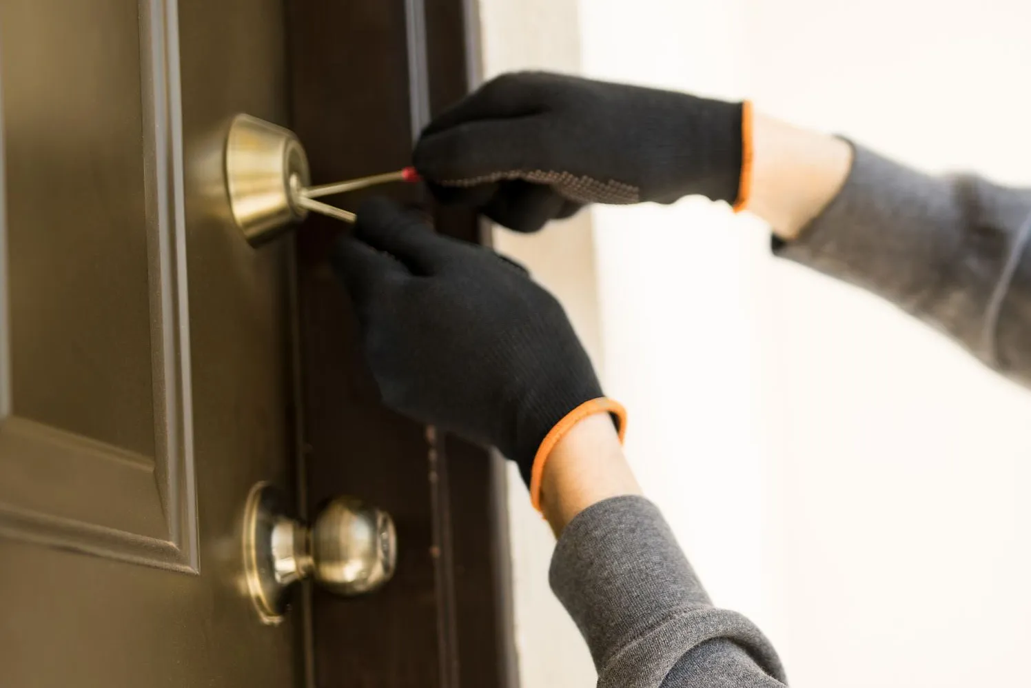 Einbrecher_profile-view-man-with-hoodie-trying-pick-lock-house-forcing-his-entry