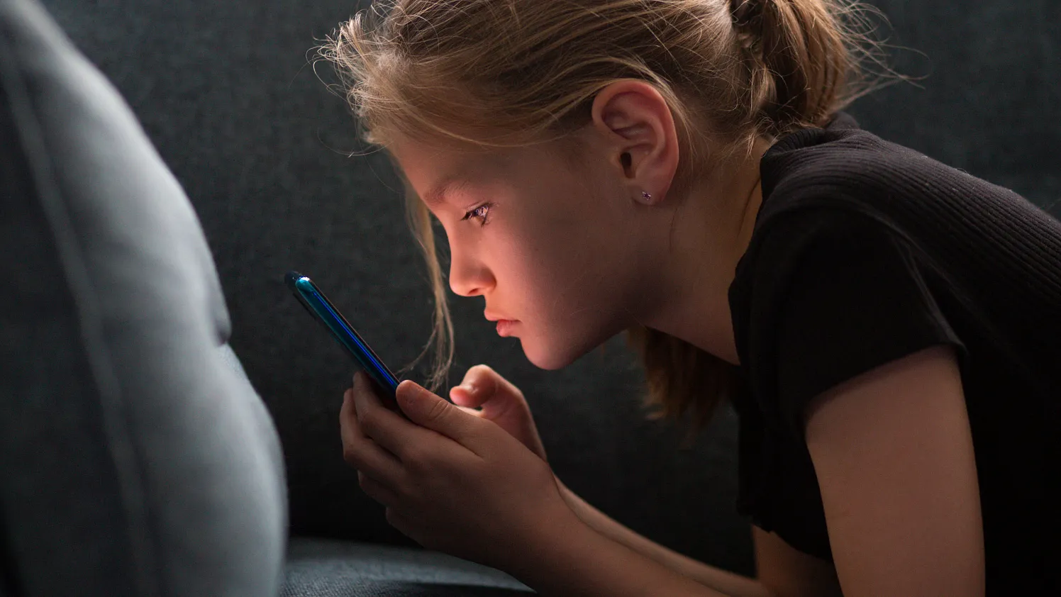 Kleines Maedchen am Handy im Dunkeln