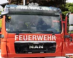 Rotes Feuerwehrauto der Marke MAN mit der Aufschrift "Hochfilzen" und "Feuerwehr" auf der Front. Teilweise verdeckte Fahrerkabine, im Freien abgestellt.