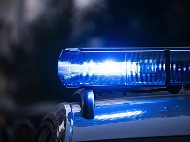 Nahaufnahme eines blauen Polizeilichts, das in der Dunkelheit blinkt. Der Hintergrund ist verschwommen, was das Hauptaugenmerk auf das Licht lenkt.