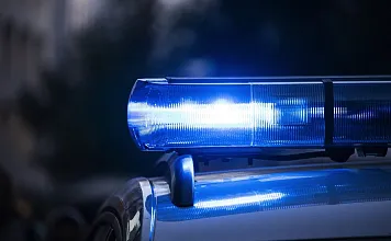 Nahaufnahme eines blauen Polizeilichts, das in der Dunkelheit blinkt. Der Hintergrund ist verschwommen, was das Hauptaugenmerk auf das Licht lenkt.